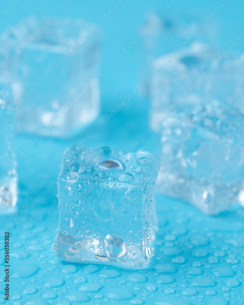 Ice cubes and ice shards with water drops on a blue background. The concept of cold and freshness Ice cubes and ice shards with water drops on a blue background. The concept of cold and freshness