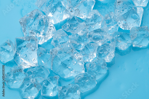 Ice cubes and ice shards with water drops on a blue background. The concept of cold and freshness