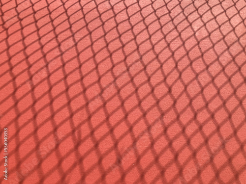 shadow of a tennis net on the red-orange ground court in natural daylight, using as background