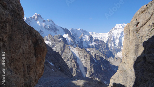 between two rocks there is a beautiful view of a huge mountain range.mountains in the snow.