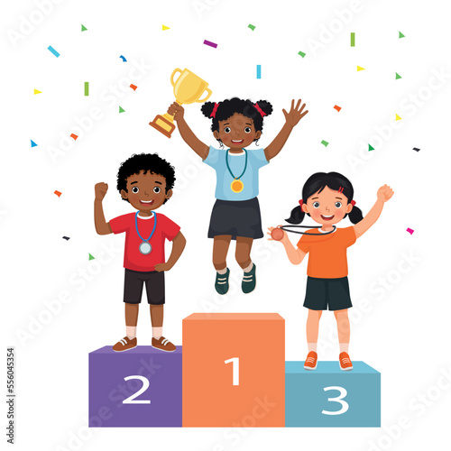 Multicultural children with medals holding gold cup trophy standing on winners podium or pedestal with first, second and third place prize celebrating winning competition