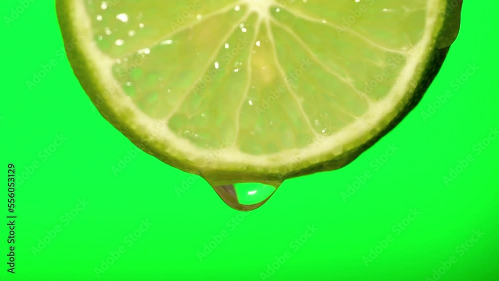 Macro image of water droplets falling from lemon slices on green background.
