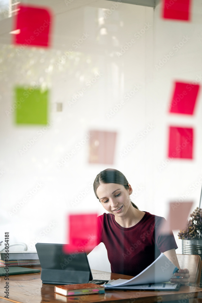 Portrait of happy business woman sitting at workplace in office. Young attractive female worker using modern laptop Portrait of happy business woman sitting at workplace in office. Young attractive female worker using modern laptop