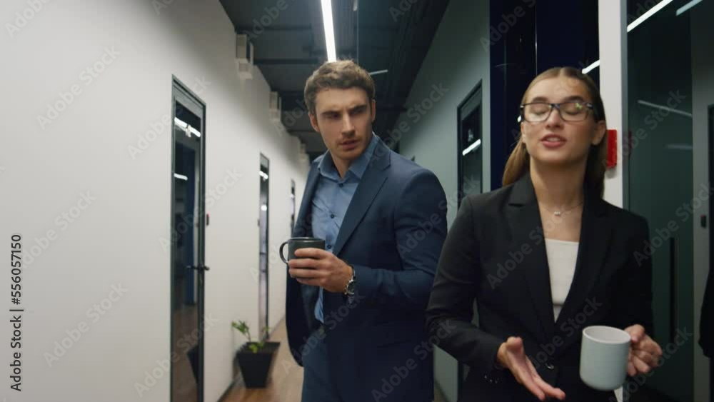 Two colleagues talking office on break. Friendly team managers walking hallway Two colleagues talking office on break. Friendly team managers walking hallway