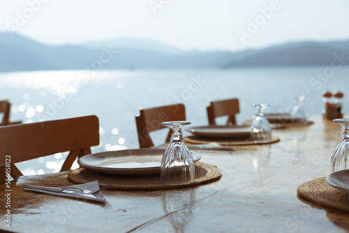 Dinner table. Open air restaurant table with and cutlery, overlooking the sea. Outdoor restaurant with views of sea. Table setting