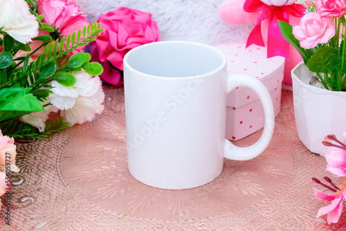 White blank coffee mug on the top of a small rounded table cloth surrounded by valentine themed decorations