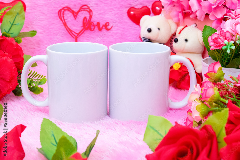 Two white blank coffee mug on the top of a fluffy pink carpet surrounded by valentine themed decorations
