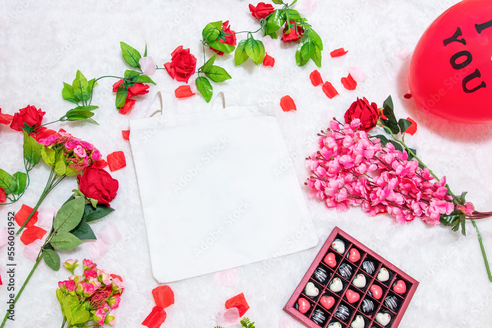 White blank tote bag on the top of a fluffy white carpet surrounded by valentine themed decorations