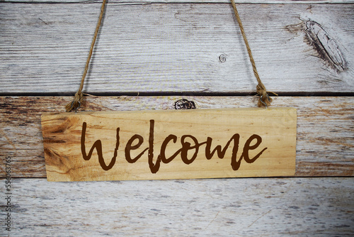 Welcome sign text message on wooden board hanging on wooden background