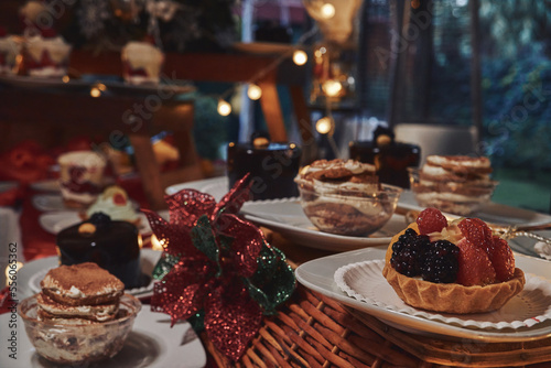 Mesa de postres. Pequeña tarta de frutos rojos sobre canasta con fondo de luces y adornos navideños