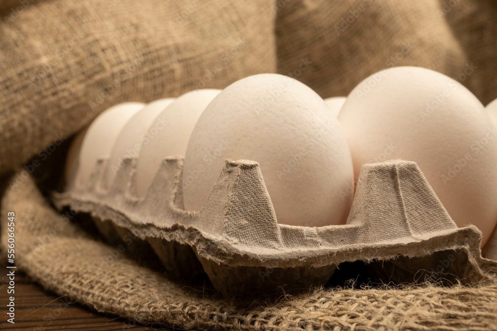 White chicken eggs in a cardboard box on the table. Close-up, selective focus. White chicken eggs in a cardboard box on the table. Close-up, selective focus.