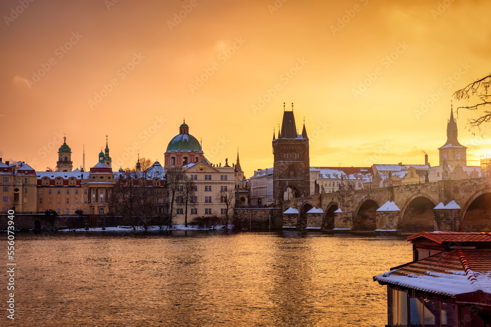 Naklejka premium Beautiful winter sunrise view of the skyline of Prague with Charles Bridge and the snow covered old town roofs, Czezch republic 