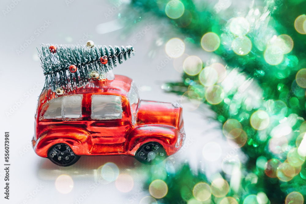 Red toy car with a Christmas tree in the palm. Festive New Year's gift. New Year post