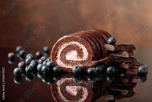 Chocolate roll cake with blueberries and a broken black chocolate bar.