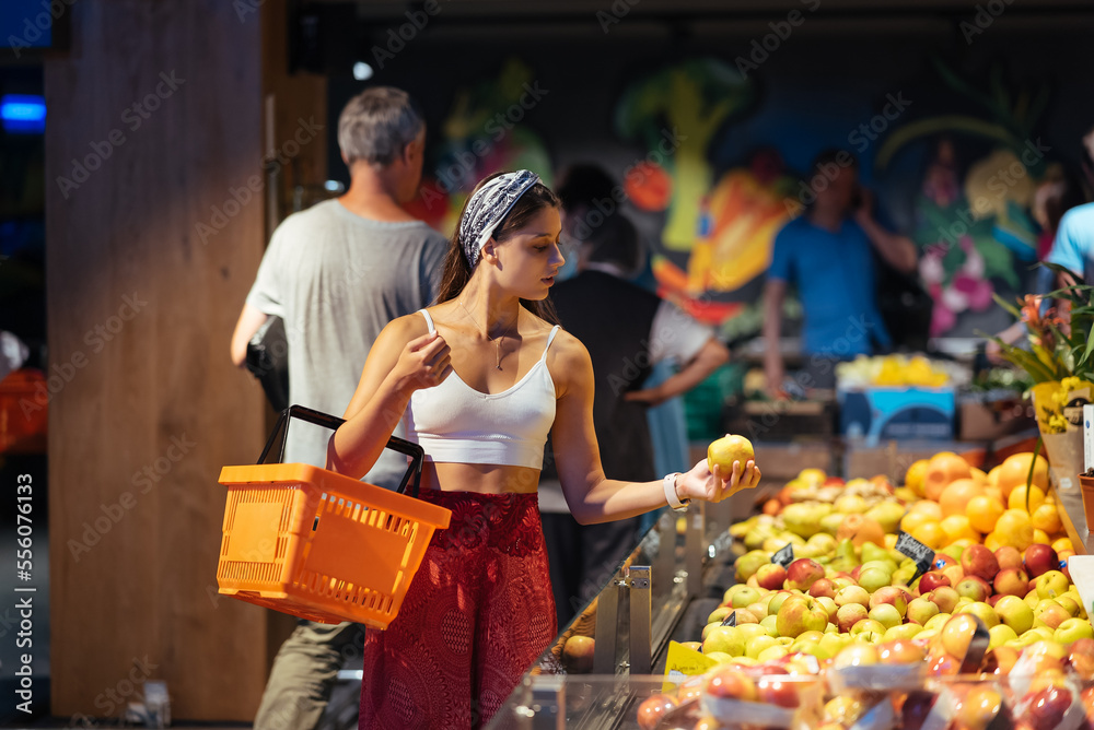 young woman do shopping in supermarket. choosing apples in store