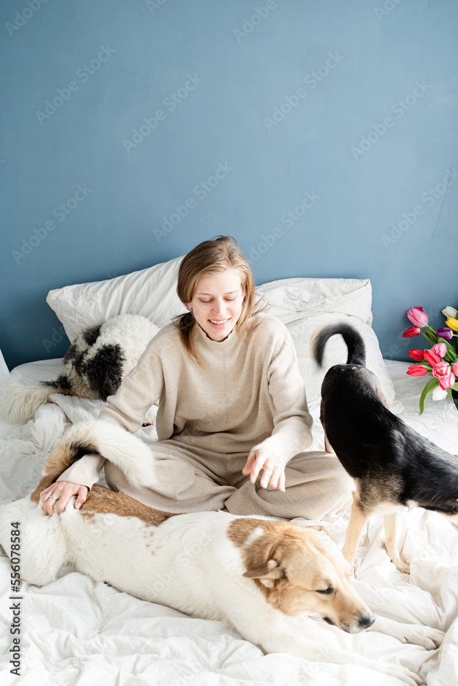 Happy young woman sitting in the bed with her dogs Happy young woman sitting in the bed with her dogs