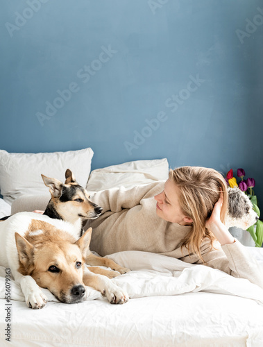 Wallpaper Mural Happy young woman lying in the bed with her dogs Torontodigital.ca