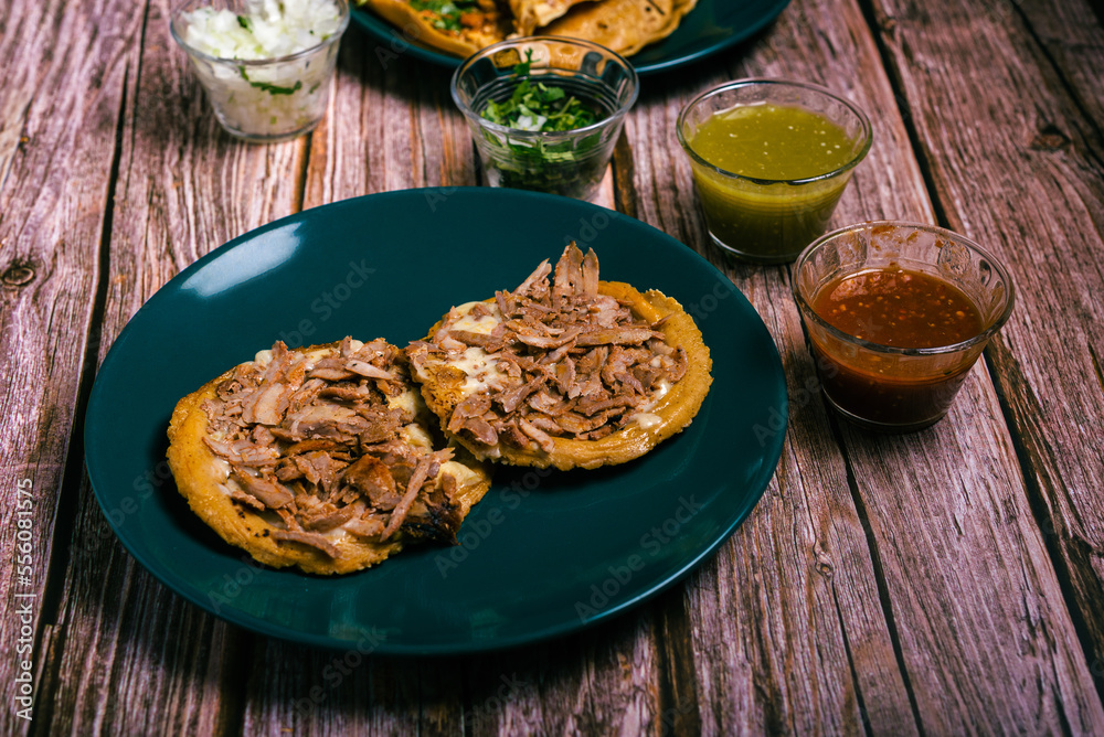 Sope pocho, typical Mexican food served with condiments on a wooden table.