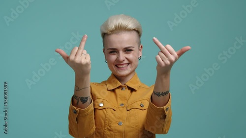 Portrait of a girl demonstrating an obscene gesture on camera. Woman with blonde, short haircut showing her strength and confidence. High quality 4k footage photo