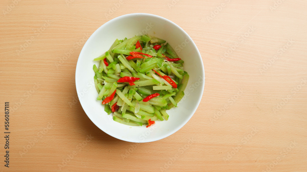 Indonesian cuisine, Tumis labu siam - Indonesian Spicy stir fry chayote, typical Indonesian daily homedish, served in white bowl over brown wooden background. Indonesian cuisine, Tumis labu siam - Indonesian Spicy stir fry chayote, typical Indonesian daily homedish, served in white bowl over brown wooden background.