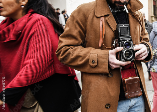 Hipster guy with the vintage camera photographing people in the city - Photojournalist with a famous retro camera taking photo in the crowd during street demonstration - Street photography style