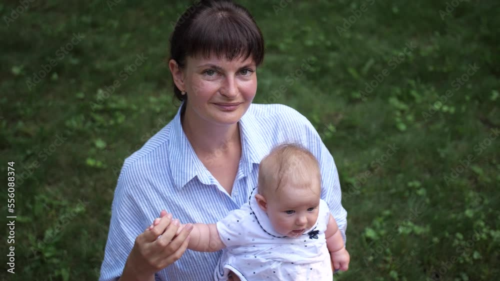 Portrait of mother with little child on background of green grass. Woman looks up at the camera. 4K Slow Mo Portrait of mother with little child on background of green grass. Woman looks up at the camera. 4K Slow Mo