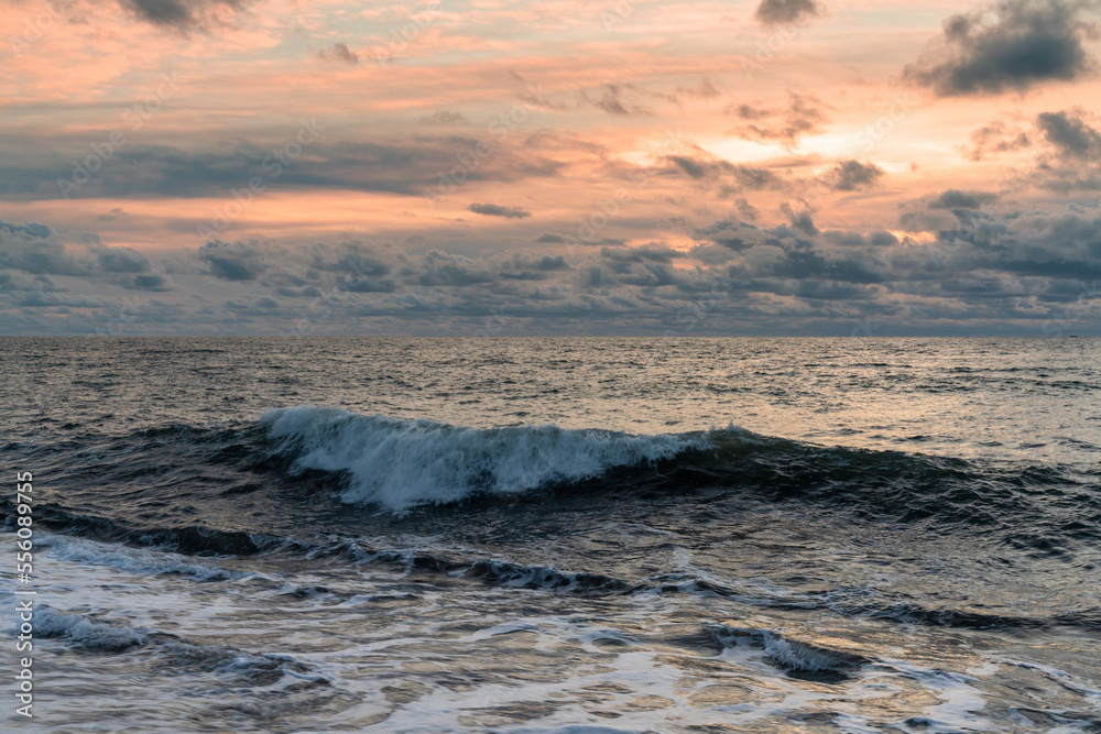 large wave breaking and rolling to shore under a stormy sunset sky large wave breaking and rolling to shore under a stormy sunset sky