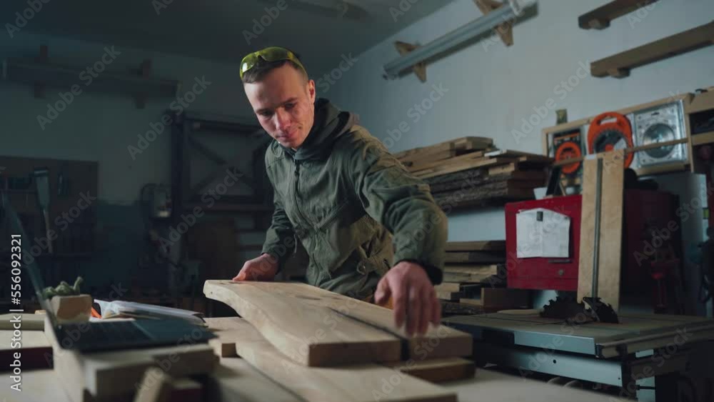 The carpenter is working. A carpenter in a carpentry checks the quality of wood.
