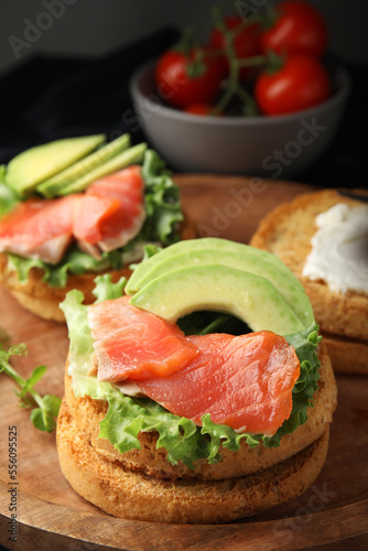 organic rusks with salmon, cream cheese and avocado served on wooden board, closeup
