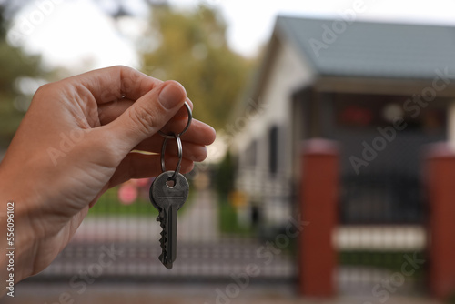 Real estate agent holding keys to new house outdoors, closeup. Space for text