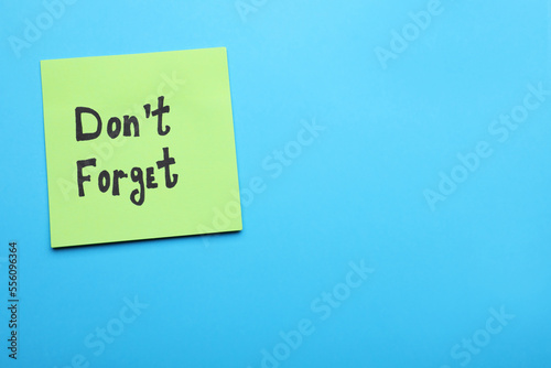 Paper note with phrase Don' t Forget on blue background, top view. Space for text