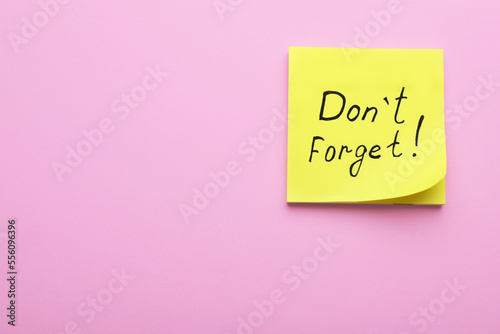 Paper note with phrase Don't Forget on pink background, top view. Space for text