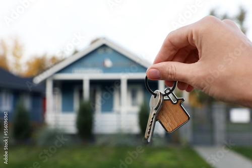 Woman holding house keys outdoors, closeup with space for text. Real estate agent