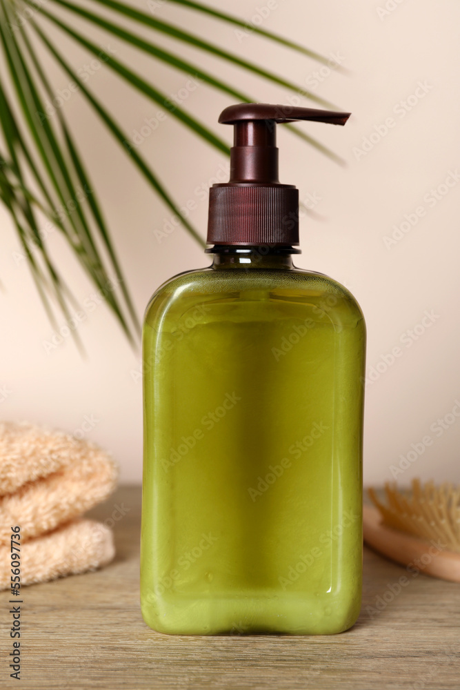 Bottle of shampoo on wooden table near beige wall Bottle of shampoo on wooden table near beige wall
