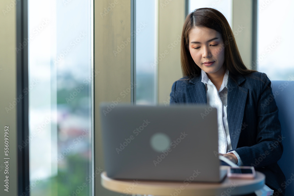 Businesswoman sitting and reading a book by the window of the office. Used in marketing business media, insurance, life insurance, finance Businesswoman sitting and reading a book by the window of the office. Used in marketing business media, insurance, life insurance, finance