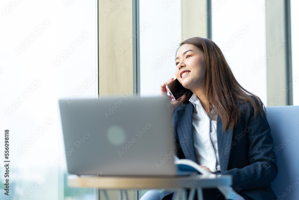 Businesswoman sitting and reading a book by the window of the office. Used in marketing business media, insurance, life insurance, finance Businesswoman sitting and reading a book by the window of the office. Used in marketing business media, insurance, life insurance, finance