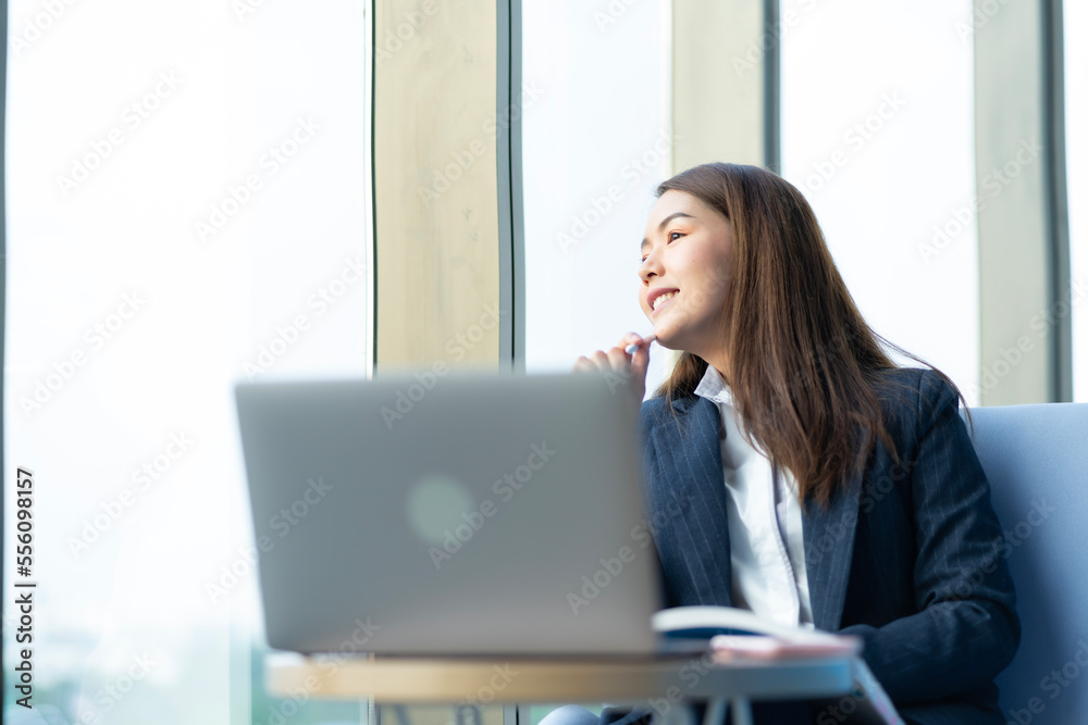 Businesswoman sitting and reading a book by the window of the office. Used in marketing business media, insurance, life insurance, finance Businesswoman sitting and reading a book by the window of the office. Used in marketing business media, insurance, life insurance, finance