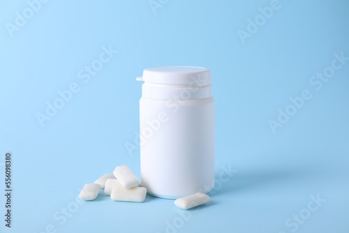 Jar with tasty chewing gums on light blue background