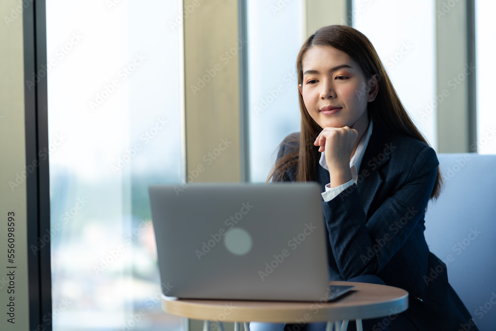 Businesswoman sitting and reading a book by the window of the office. Used in marketing business media, insurance, life insurance, finance Businesswoman sitting and reading a book by the window of the office. Used in marketing business media, insurance, life insurance, finance