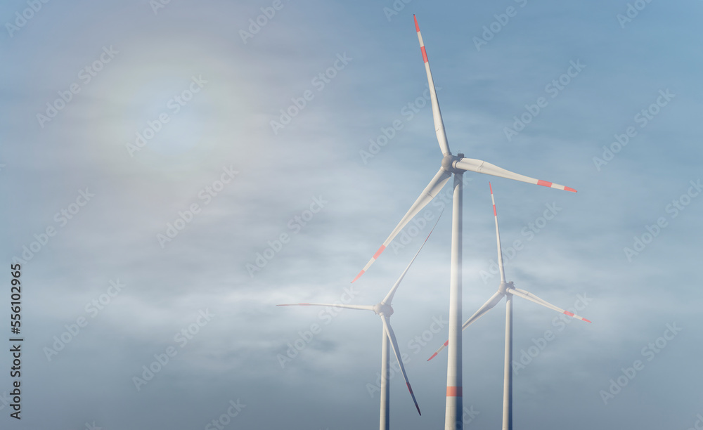 Wind turbines in foggy conditions in the diffuse backlight of the sun.