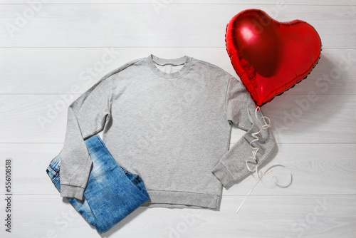 Grey sweatshirt mockup. Valentines Day concept shirt, balloons heart shape on wooden background. Copy space, template blank front view clothes. Romantic outfit. Flat lay holiday fashion