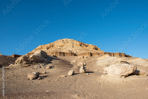 Rocky slope in a desert with pyramid mountain