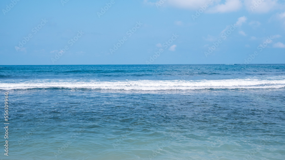 Sunny day beach with blue water and ocean waves