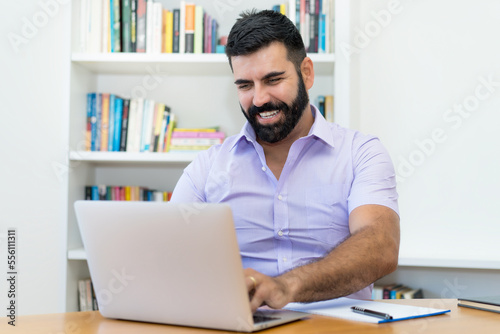 Successful hispanic businessman with beard working at computer