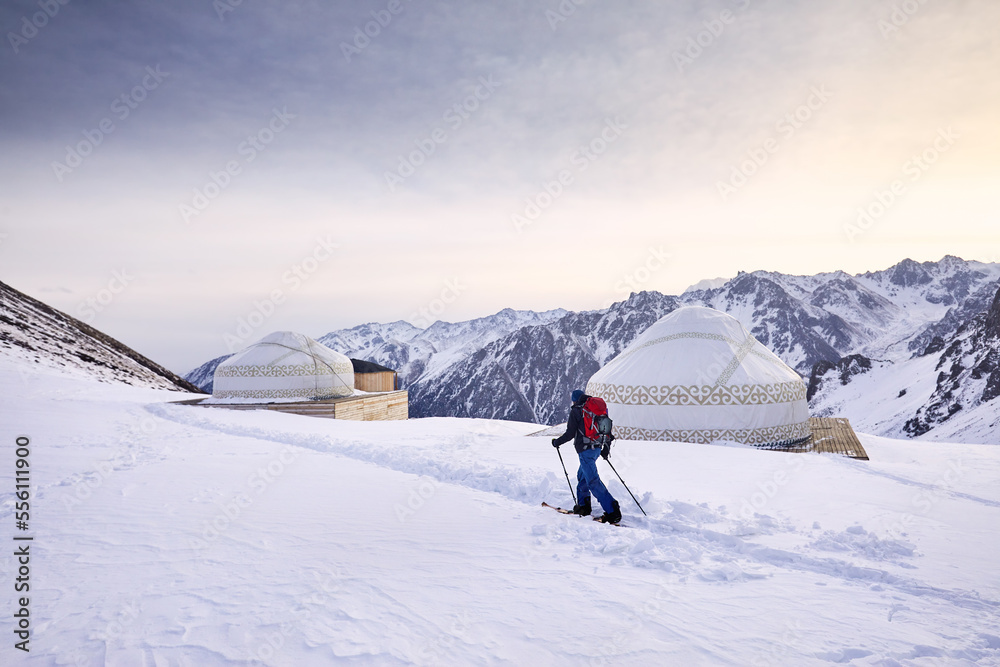Man skiing near yurt house snowy mountains