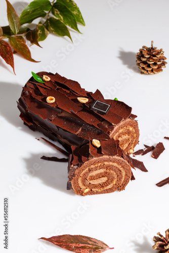 Sliced chocolate cake roll with buttercream and hazelnuts on white background
