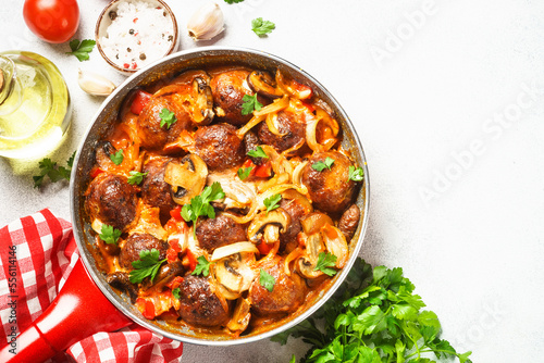 Meatballs with mushrooms in tomato sauce in a frying pan.