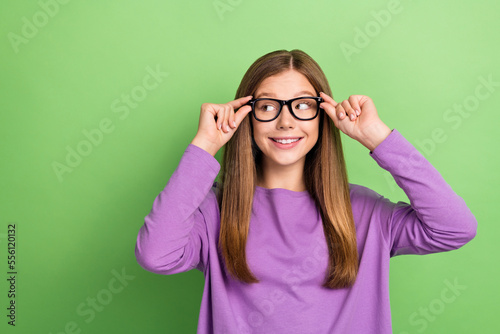 Photo of intelligent pretty lady wear stylish clothes look empty space promoting eyewear isolated on green color background © deagreez