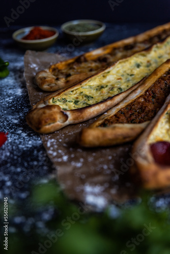 Turkish pide pastry baked in a stone oven served on stone plate with minced meat and cheese