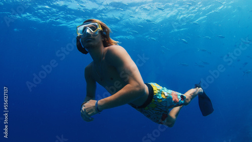 Man swims underwater and watches fish